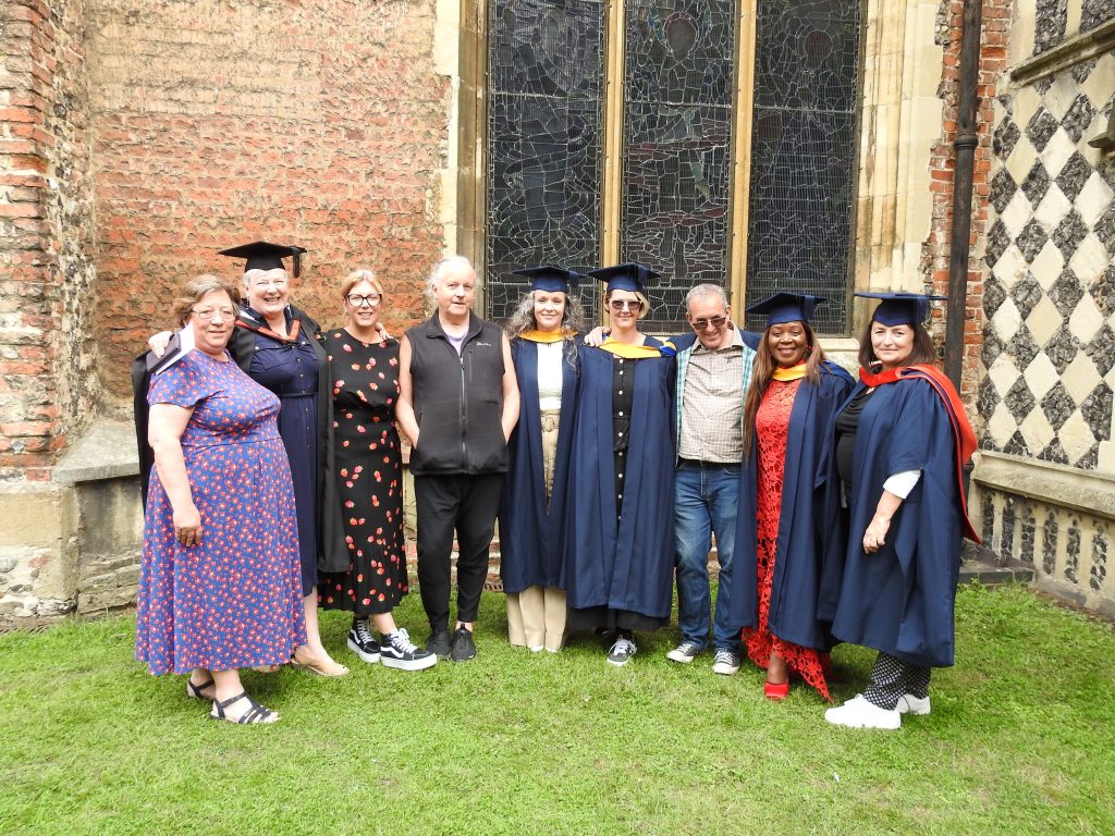 Renew graduates gather with Renew tutors at their graduation ceremony, wearing cap and gown outside the Cathedral