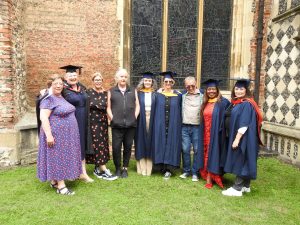 Renew graduates gather with Renew tutors at their graduation ceremony, wearing cap and gown outside the Cathedral