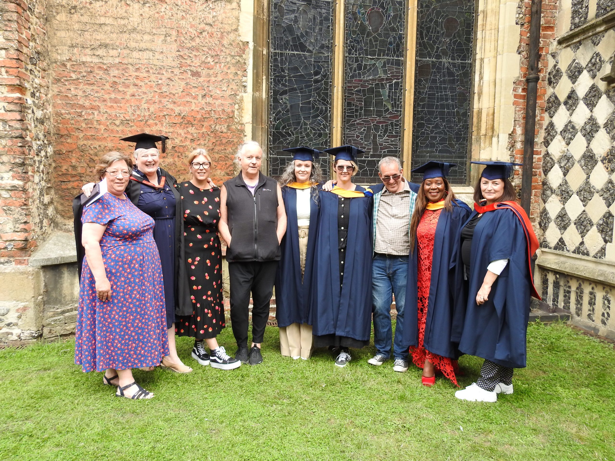 Renew graduates gather with Renew tutors at their graduation ceremony, wearing cap and gown outside the Cathedral